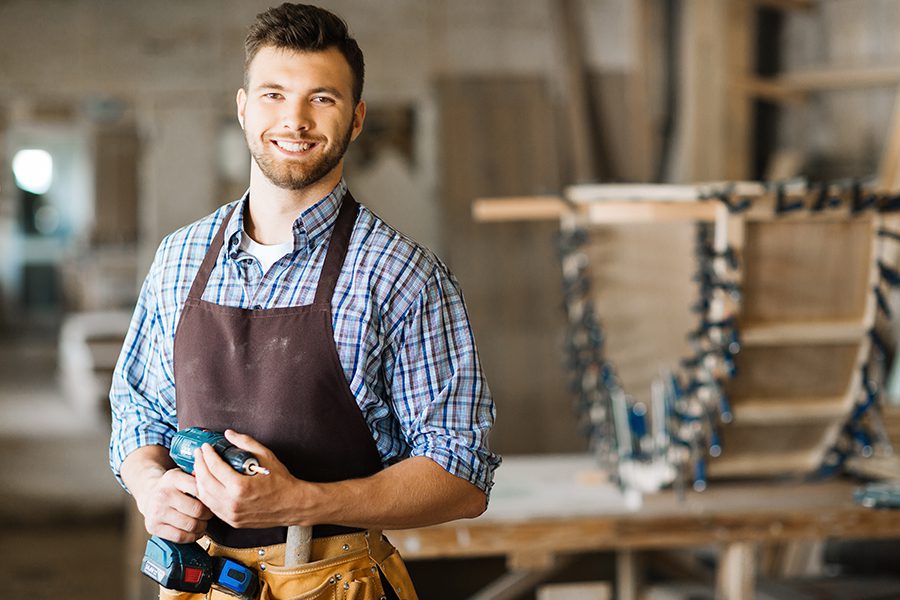 Specialized Business Insurance - Portrait of Craftsman with Drill Standing in a Spacious Workshop